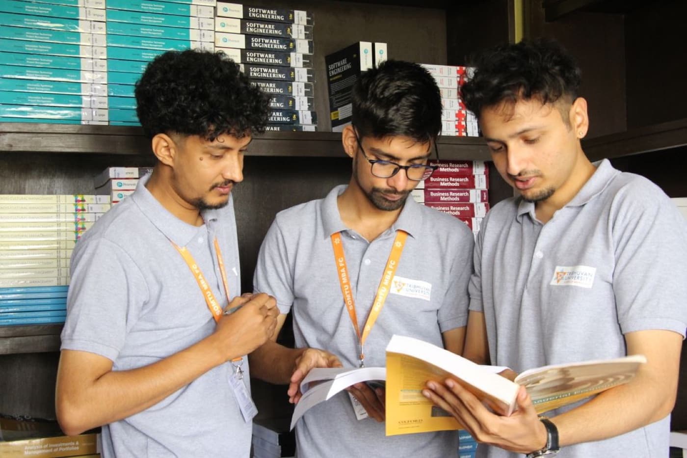 Three MBA students in a university library reading business textbooks together