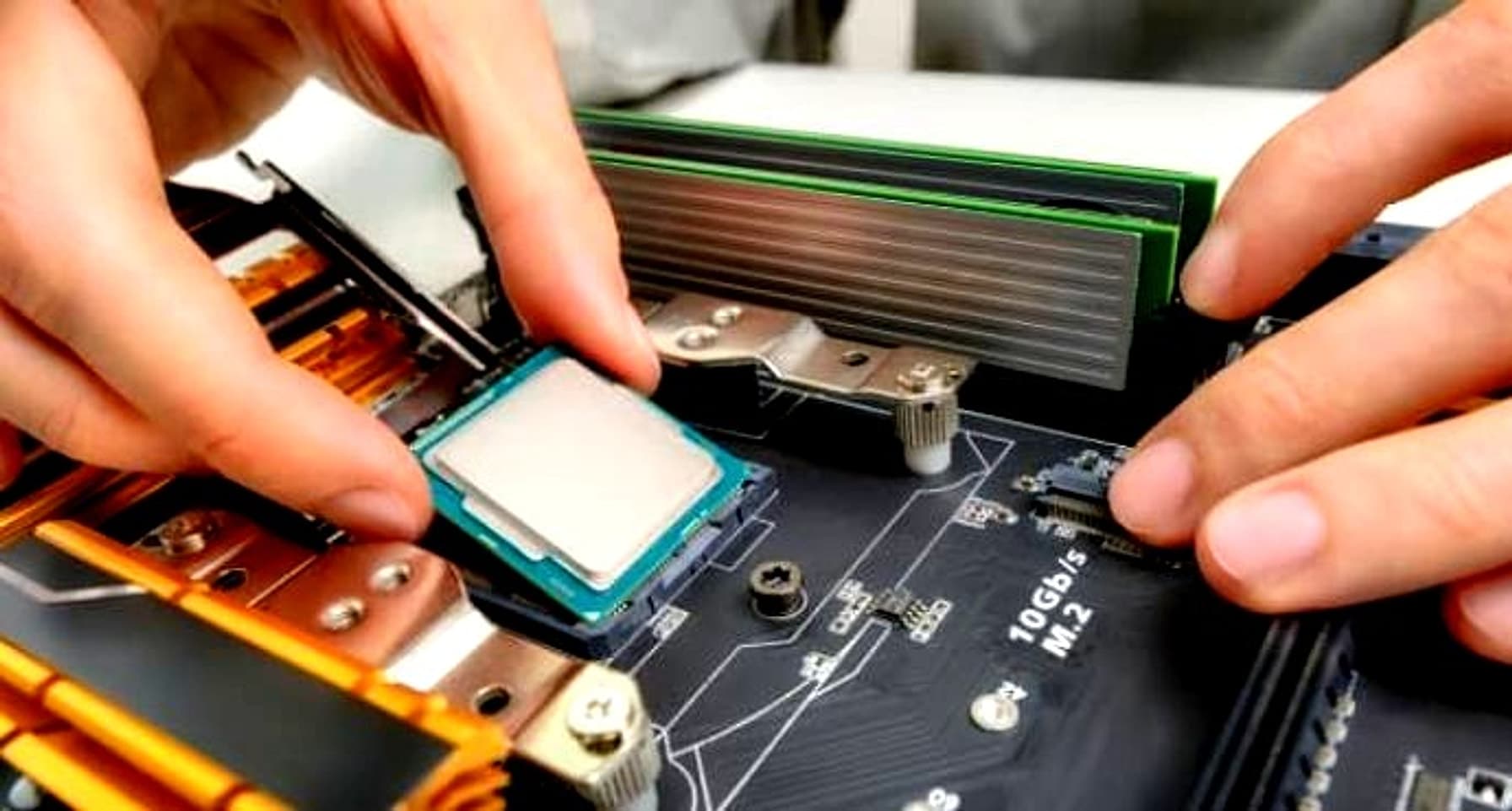 Close-up of hands installing a CPU and RAM module onto a computer motherboard during a hardware upgrade